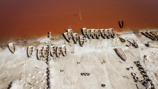 SENEGAL-TOURISM-ECONOMY Luftaufnahme von Booten am Ufer eines rosafarbenen Sees.