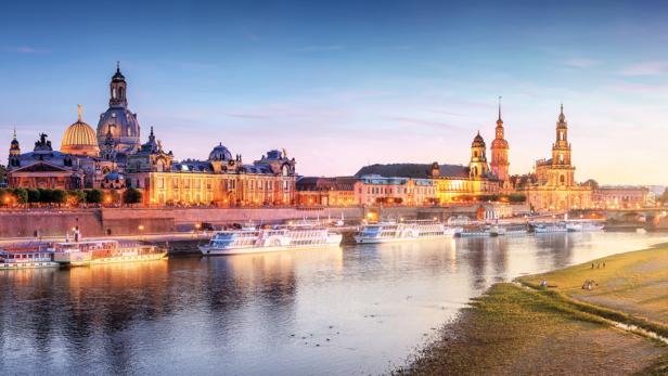Die Altstadt einer Stadt von der anderen Seite des Flusses gesehen, in der Abenddämmerung.