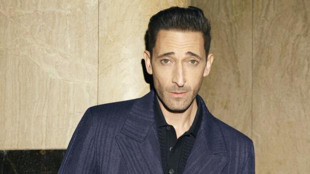 Adrien Brody trägt einen dunkelblauen Anzug.