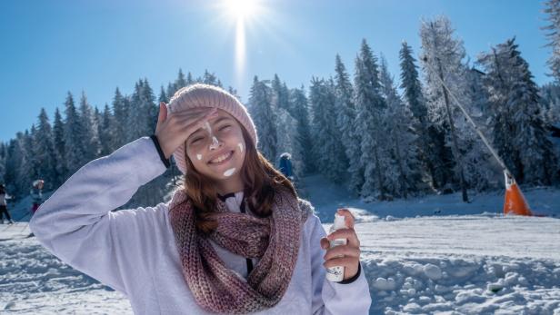 A teenage girl applies sunscreen while skiing. Sonnencremes im Test: Gut für die Haut, weniger für die Umwelt