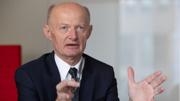 Ein Mann im Anzug gestikuliert während eines Gesprächs.