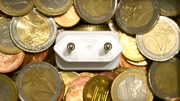 Ein Stromstecker schaut zwischen vielen Euro-Münzen hervor