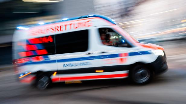 Eine weiße Ambulanz mit Blaulicht fährt schnell durch die Stadt.