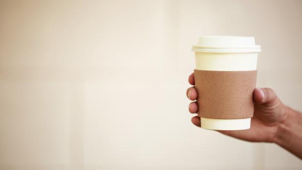 Paper cup of takeaway coffee in the hand All you can drink: Diese Wiener Bäckerei-Kette startet jetzt mit Kaffee-Pauschale