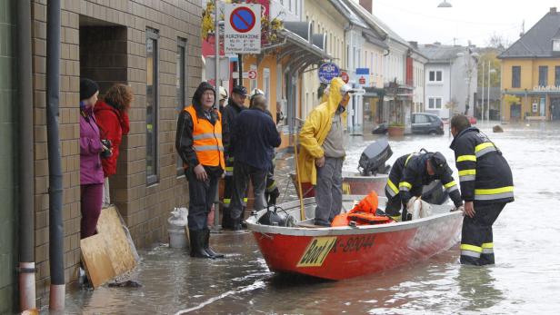 Ein überflutetes Stadtzentrum mit Feuerwehrleuten in einem Rettungsboot.