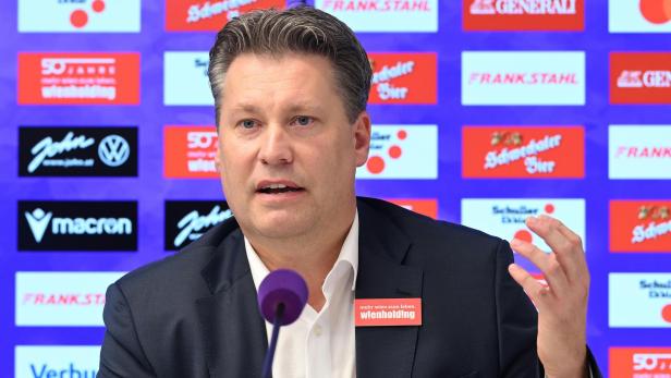 Ein Mann spricht vor einem Hintergrund mit Sponsorenlogos wie Generali und Frank Stahl.