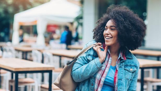 Beautiful smiling girl outdoors in the city Eine junge Frau mit einer Tasche