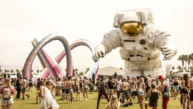 Coachella: Zahlreiche Festival-Besucher sammeln sich auf einer Wiese vor einer riesigen Astronauten-Statue.
