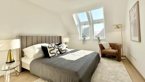 Schlafzimmer mit einem Bett, einem Stuhl und einem Fenster, das Tageslicht hereinlässt.