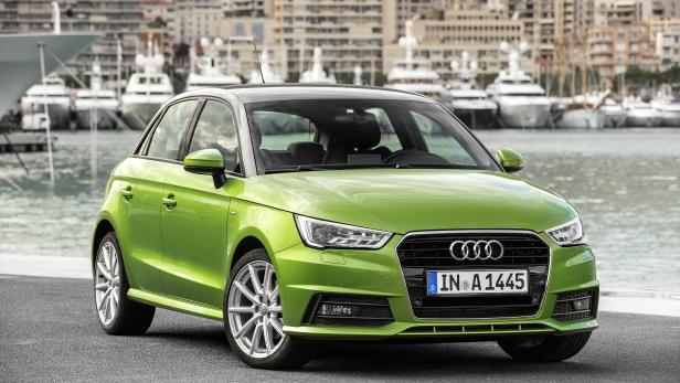 Ein grüner Audi A1 steht vor einem Hafen mit Yachten und Gebäuden im Hintergrund.