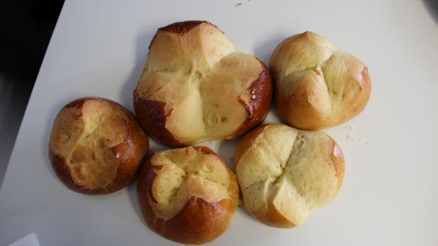 Fünf Kaisersemmeln liegen auf einer weißen Oberfläche.