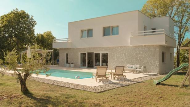 Ein Gebäude von außen, weiß, mit Pool, Liegestühlen und Garten