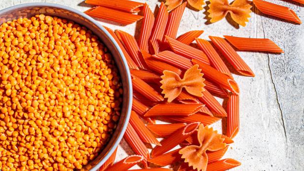 Rote Linsen und rote Nudeln in Form von Penne und Farfalle.