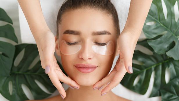 Woman with eye patches having face massage