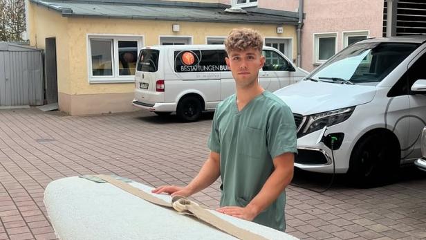 Bestatter Luis Bauer steht vor einem weißen Sarg