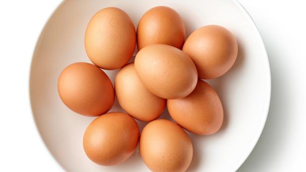 Acht braune Eier liegen in einer weißen Schüssel.