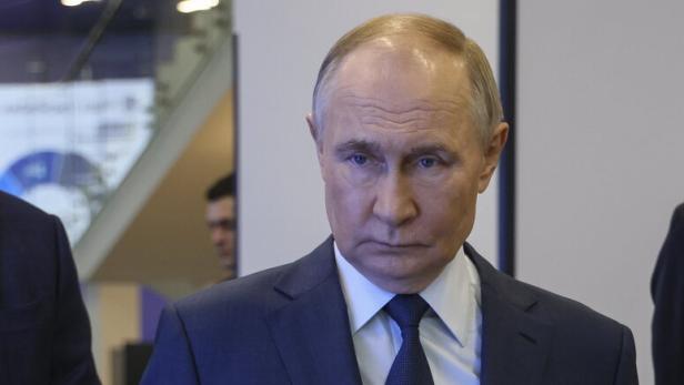 Wladimir Putin bei einer Veranstaltung, sein Spiegelbild ist auf einer glänzenden Oberfläche zu sehen.