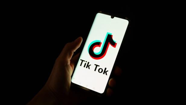 Eine Hand hält ein Smartphone, auf dessen Bildschirm das TikTok-Logo zu sehen ist.