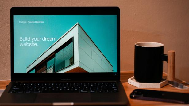 Der Bildschirm eines Laptops, daneben steht eine Tasse.