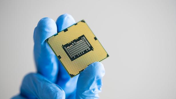 Behandschuhte Hand hält ein Elektronikbauteil mit Goldkontakten