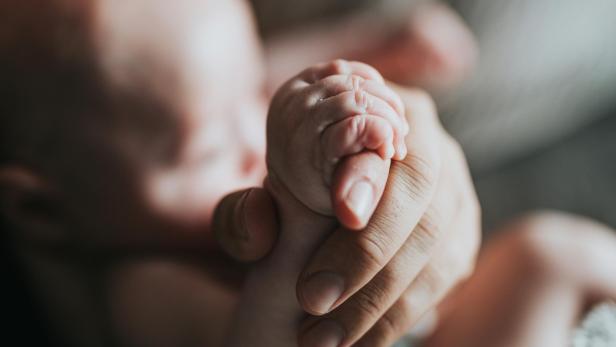 Frauenhand hält kleine Babyhand
