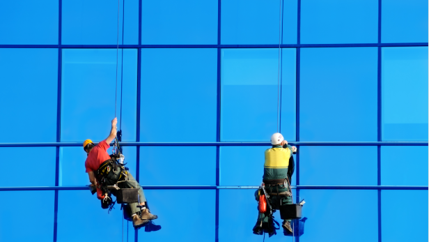 Zwei Fensterputzer hängen an der Fassade eines Hochhauses.