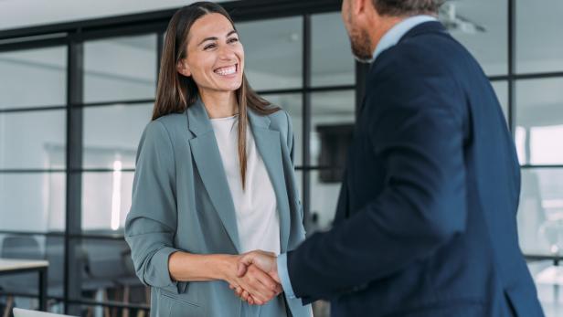 Business persons shaking hands across the table. Betriebliche Zusatzpension: Sicher vorsorgen fürs Alter