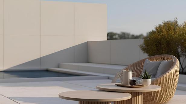 Ein Rattansessel und ein Tisch mit Geschirr stehen auf einer Terrasse neben einem Pool.