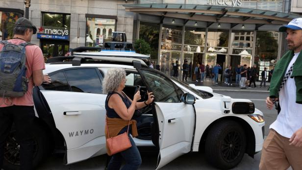 FILE PHOTO: Waymo driverless taxi Passagiere steigen in ein fahrerloses Taxi von Waymo ein.