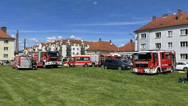 Feuerwehrautos stehen auf Wiese vor Häusern 
