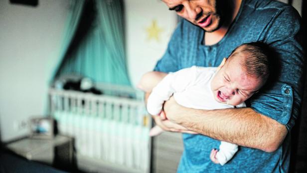 Kind in eigenem Zimmer Vater hält sein Kind vor einem Kinderbett im Kinderzimmer