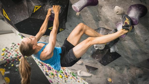 Eine Frau klettert in einer Boulderhalle.