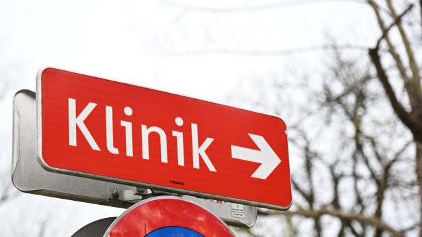 Ein rotes Hinweisschild mit weißer Aufschrift „Klinik“ und einem Pfeil nach rechts.