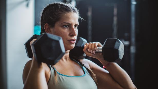 Eine Frau hält zwei Kurzhanteln in den Händen.