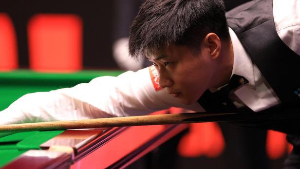World Snooker Championship Ein Snookerspieler zielt mit dem Queue auf den Spielball.