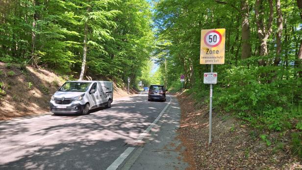 Drei Pkw fahren an einer Tafel mit Tempo-50-Beschränkung im Wienerwald vorbei.