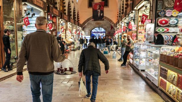 Ein Mann trägt Tee durch einen belebten Markt in Istanbul, Türkei.