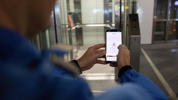 Mann steht mit Handy vor Aufzug in U-Bahn