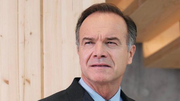 Ein Mann in Anzug und Hemd blickt nachdenklich zur Seite.