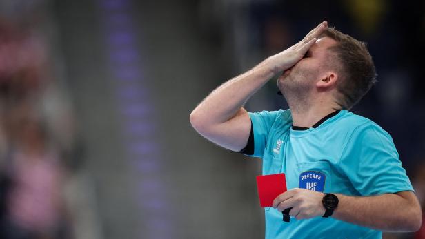 HANDBALL-OLY-2024-QUALIFIER-MEN-CRO-AUT Ein Handballschiedsrichter hält eine rote Karte in der Hand und bedeckt sein Gesicht.