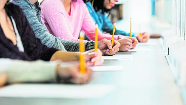 Cropped view of group of teenagers taking a test Cropped view of group of teenagers taking a test