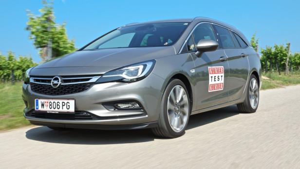 Ein grauer Opel Astra Kombi fährt auf einer Landstraße.