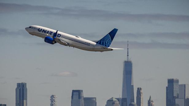 ein United-Airlines Flugzeug im Steigflug vor einer Hochhaus-Skyline