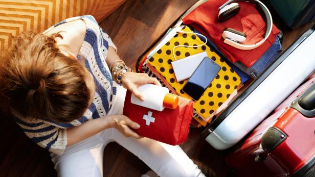 Frau packt ihren Koffer inklusive eines medizinischem Paket