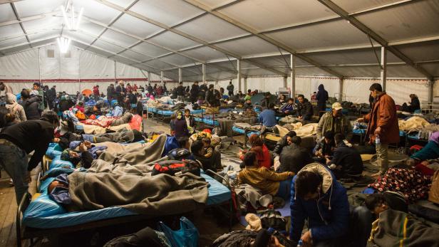 Viele Menschen ruhen sich in einem Notlager auf Feldbetten aus.