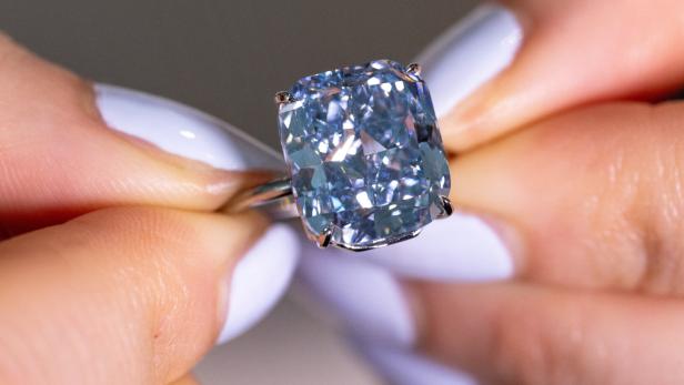 A Sothebys staff holds "The Mediterranean Blue" diamond during an auction preview in Geneva
