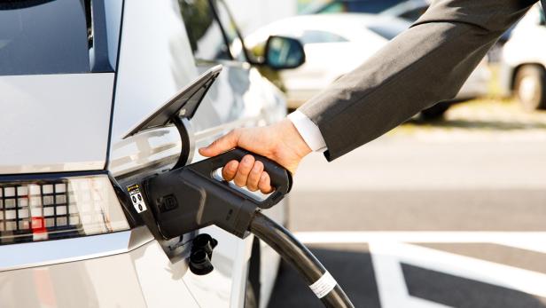 Ein Mann im Anzug lädt sein E-Auto an einer Ladestation von Wien Energie auf. 