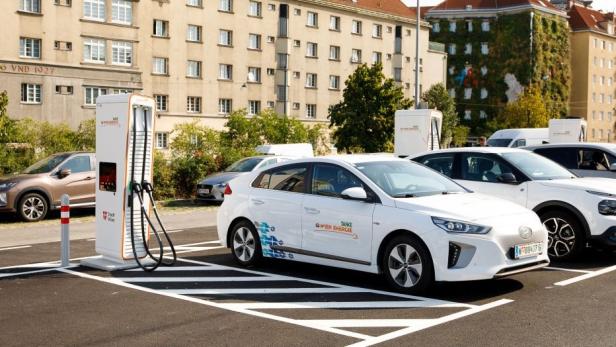 Ein E-Auto auf einem Parkplatz in Wien neben einer E-Ladestation von Wien Energie. 