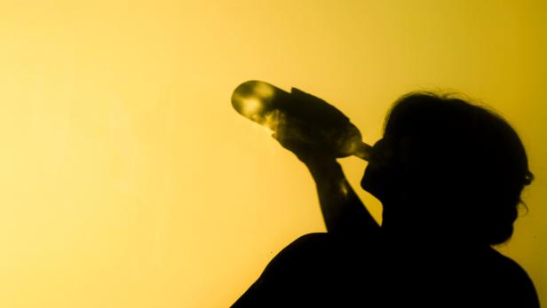 Schatten eine Frau, die Alkohol aus einer Flasche trinkt.