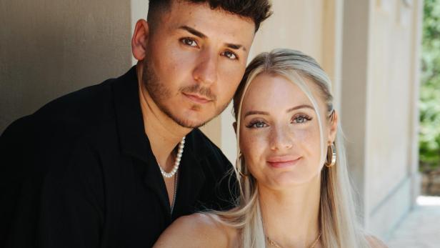 Saskia und Enrico mussten die Show verlassen. Grund dafür soll eine verbale Entgleisung des Teilnehmers gewesen sein. Braunhaariger Mann mit schwarzem Shirt und blonde Frau im grünen Kleid sitzen auf dem Boden und lächeln in die Kamera